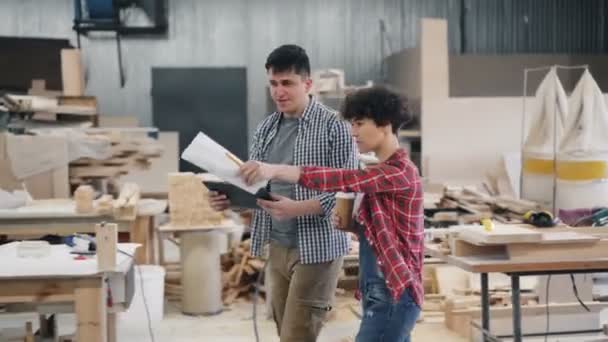 Propriétaires d'entreprise parlant dans un atelier en bois tenant café, papiers et tablette — Video