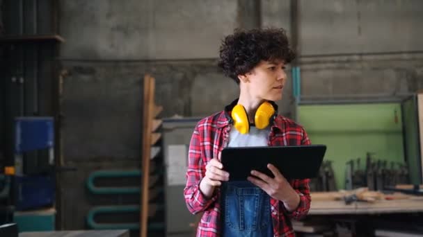 Serieuze vrouwelijke timmerman werken met Tablet in workshop wandelen aanraken scherm — Stockvideo