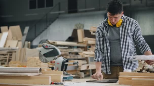 Mann liest Dokument, das mit Tablet in Holzwerkstatt mit Touchscreen arbeitet — Stockvideo