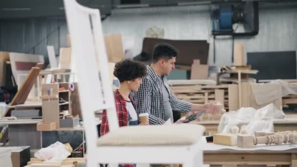 Menschen, die in der Werkstatt bei Kaffee und Tablet über die Arbeit sprechen — Stockvideo