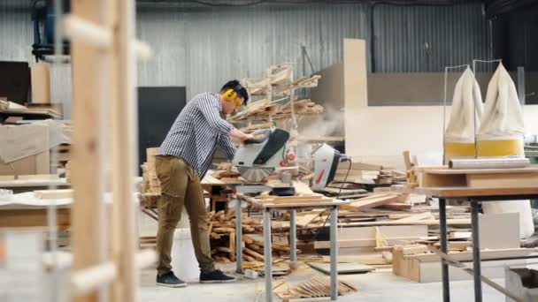 Αρσενικό εργαζόμενο χρησιμοποιώντας ηλεκτρικό πριόνι σε εργαστήριο ξύλου πριονίσματος ξυλείας εργασίας μόνο — Αρχείο Βίντεο