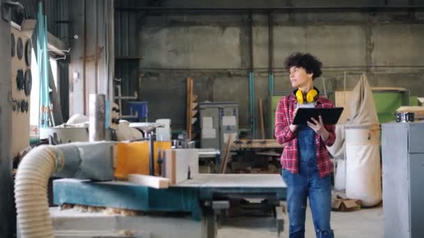 Mädchen arbeitet mit Tablet in Holzwerkstatt und schaut sich mit Gadget um — Stockvideo