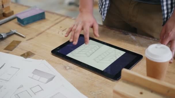 Крупный план мужской руки касаясь экрана планшета в деревянной мастерской в помещении — стоковое видео
