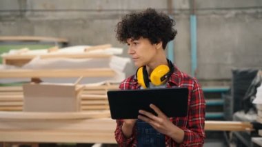 Tablet kullanarak ahşap atölyesinde envanter le meşgul işçi etrafa bakarak yürüyüş