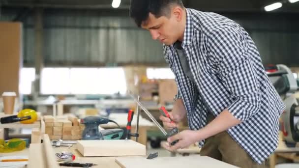 Männlicher Holzarbeiter fixiert Stück Holz auf Arbeitstisch mit speziellen Instrumenten — Stockvideo