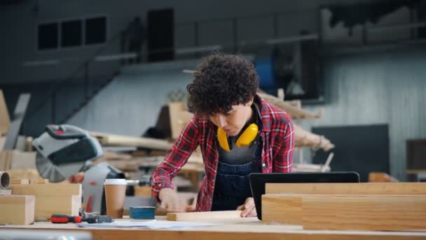 Κορίτσι απασχολημένη στίλβωση ξύλου με λειαντικό μπλοκ στο χώρο εργασίας στο εργαστήριο ξυλείας — Αρχείο Βίντεο