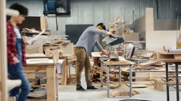 Ξυλουργός απασχολημένος πριονίζω ξύλο με κυκλικό πριόνι στέκεται στο εργαστήριο — Αρχείο Βίντεο
