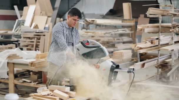 Timmerman schoonmaken cirkelzaag van zaagsel werken in workshop binnenshuis — Stockvideo