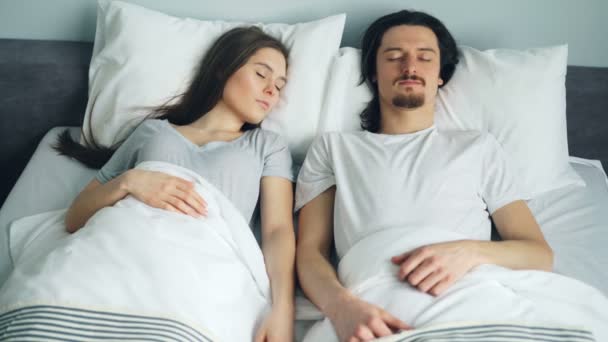 สามีและภรรยานอนบนเตียงที่บ้านปกคลุมด้วยผ้าห่มผ่อนคลาย — วีดีโอสต็อก