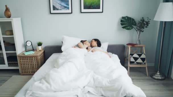 Zoom in di uomo e donna abbracciare parlando strofinando nasi baciare a letto — Video Stock