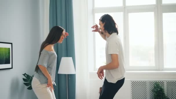 Juguetones estudiantes pareja divirtiéndose en casa bailando en la cama en el dormitorio — Vídeos de Stock