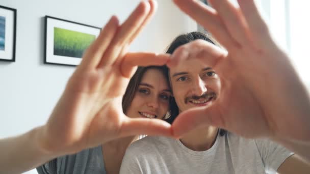 Retrato de pareja haciendo corazón con las manos mirando a la cámara y sonriendo — Vídeos de Stock