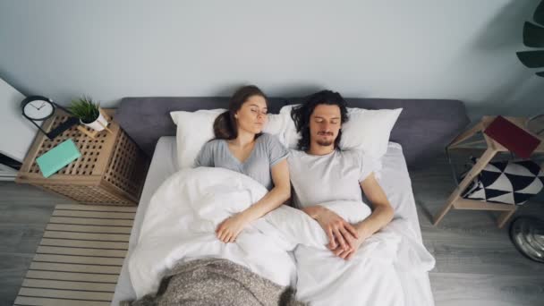 Άντρας και γυναίκα που κοιμούνται στο κρεβάτι και μετά ξυπνούν και σπεύδουν από την κρεβατοκάμαρα — Αρχείο Βίντεο