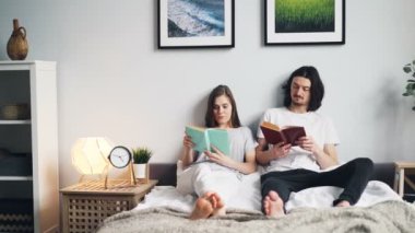 Güzel çift birlikte hobi zevk evde yatakta oturan kitap okuma