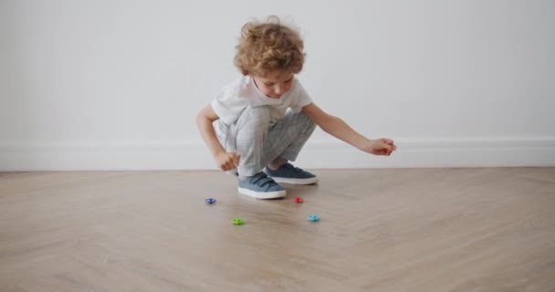 Criança adorável em roupas casuais brincando com brinquedos no chão no apartamento — Vídeo de Stock