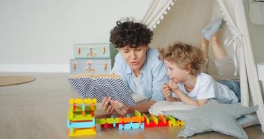 Neşeli çocuk, anne kapalı çadırda kitap okurken gülerek hikaye nin tadını çıkarıyor