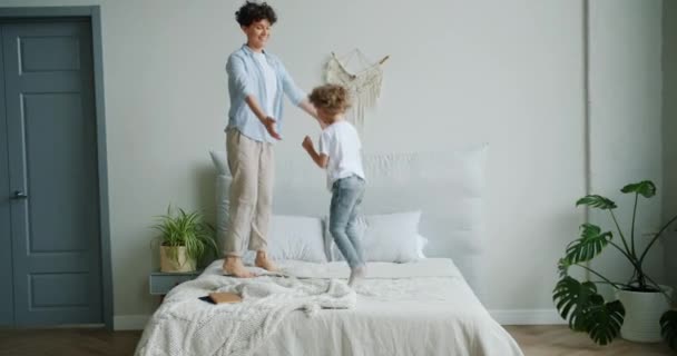 Movimento lento de feliz mãe e filho pulando na cama se divertindo juntos — Vídeo de Stock