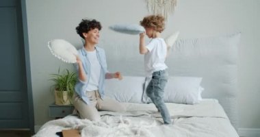 Mutlu aile anne ve oğlu yatakta evde yastık mücadele ve gülüyor
