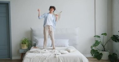 Yatakta dans eden kadının yavaş çekimde eğlenen kulaklıkla müzik dinlemesi