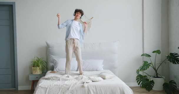 Slow motion of woman dancing on bed listening to music in headphones having fun — Stock Video