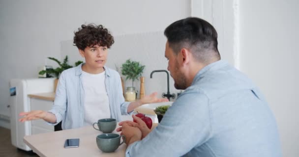 Nešťastná manželka bojuje s manželem při snídani v kuchyni, mluvící gestikulkou — Stock video