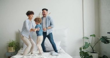 Anne baba ve oğlu birlikte evde yatak odasında yatakta dans atlama