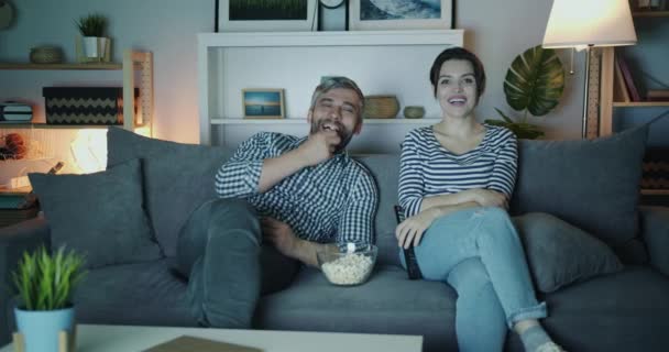 Homem e mulher desfrutando de show engraçado na TV à noite rindo assistindo TV — Vídeo de Stock