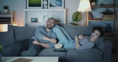 Güzel çift gece gülerek rahatlatıcı daire kanepede Tv izlerken