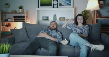 Kız ve adam patlamış mısır yiyor ve dairede gece tv izliyor