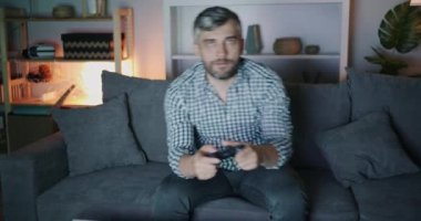 Evde gece kameraya bakarak video oyunu oynayan mutlu adam Portresi