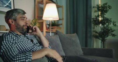 Yakışıklı adam gece evde gesturing cep telefonu konuşuyor