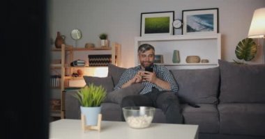 Gece evde gülen akıllı telefon kullanan yakışıklı adam portresi