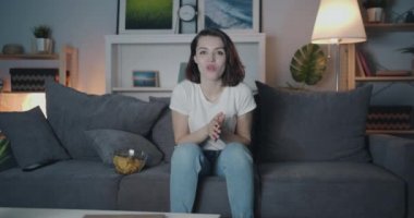 Mutlu bayan gece tv izlerken tek başına kanepede otururken eğlenerek gülüyor