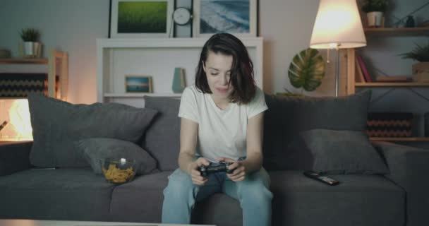 有吸引力的年轻女士玩视频游戏在家里在晚上，然后拍手 — 图库视频影像