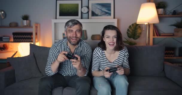 Chica y chico disfrutando de videojuegos en casa tarde en la noche, mujer ganando — Vídeos de Stock