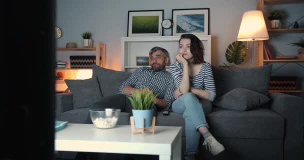 Casal jovem assistindo filme chato na TV em casa à noite bocejando relaxante — Vídeo de Stock