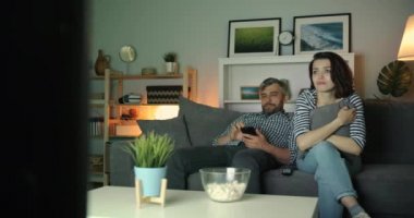 Gece evde akıllı telefon kullanan adam ağlarken televizyon izleyen kadın