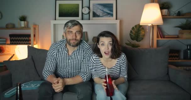 Boldog pár sportrajongó nézi játék TV éjjel habbal és ital — Stock videók