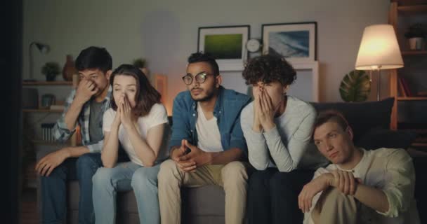 Multiracial group of young people watching TV at home at night yawning — Stock Video