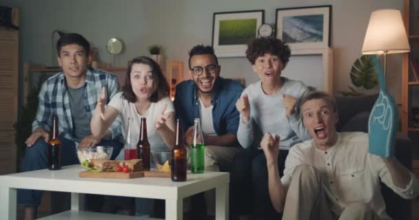 Slow motion portrait of excited students watching sports game on TV at night — Stock Video