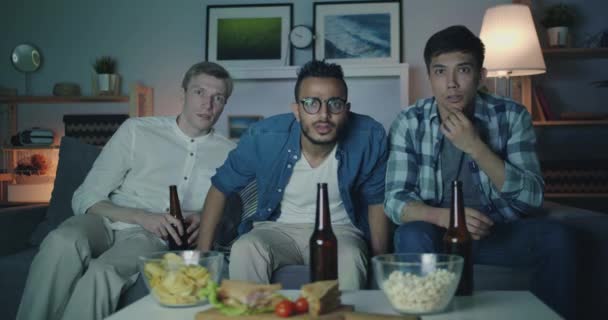Retrato de chicos guapos amigos viendo la televisión por la noche con caras asustadas — Vídeos de Stock