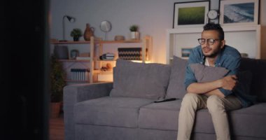 Üzgün Arap adam gece kanepede tek başına oturan gözleri silerek ağlayarak Tv izlerken