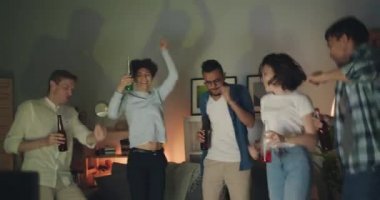 Heyecanlı kızlar ve çocuklar içecekler ile şişe tutarak evde parti dans