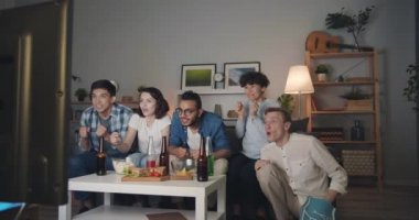 Çok ırklı grubun geceleri tv'de eğlenip spor izlemesinin yavaş hareketleri