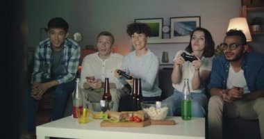 Erkekler eğlenirken evde video oyunu oynayan genç kadınlar