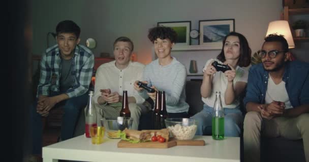 Jonge vrouwen spelen video game thuis terwijl mannen ondersteunen plezier — Stockvideo