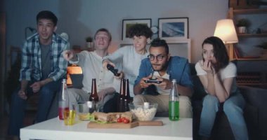 Mutlu arkadaşlar geceleri evde video oyunu oynarken gülerek eğleniyor