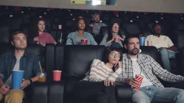 Çekici erkek ve kadınlar aperatifler ve içecekler ile sinemada oturan film izlerken — Stok video