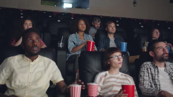 Mujer corriendo por la sala de cine mientras los espectadores jóvenes viendo películas — Vídeo de stock