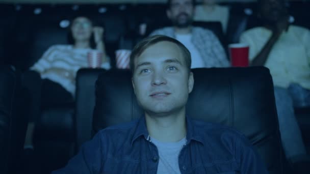 Медленное движение счастливого человека, смотрящего фильм и поедающего попкорн в кино — стоковое видео
